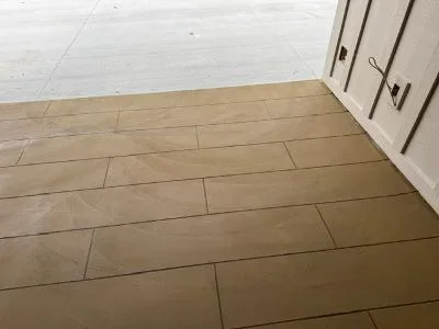 Newly coated wood deck with tan finish in staggered plank pattern