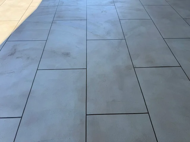 Large-format gray porcelain tiles installed in running bond pattern on outdoor deck