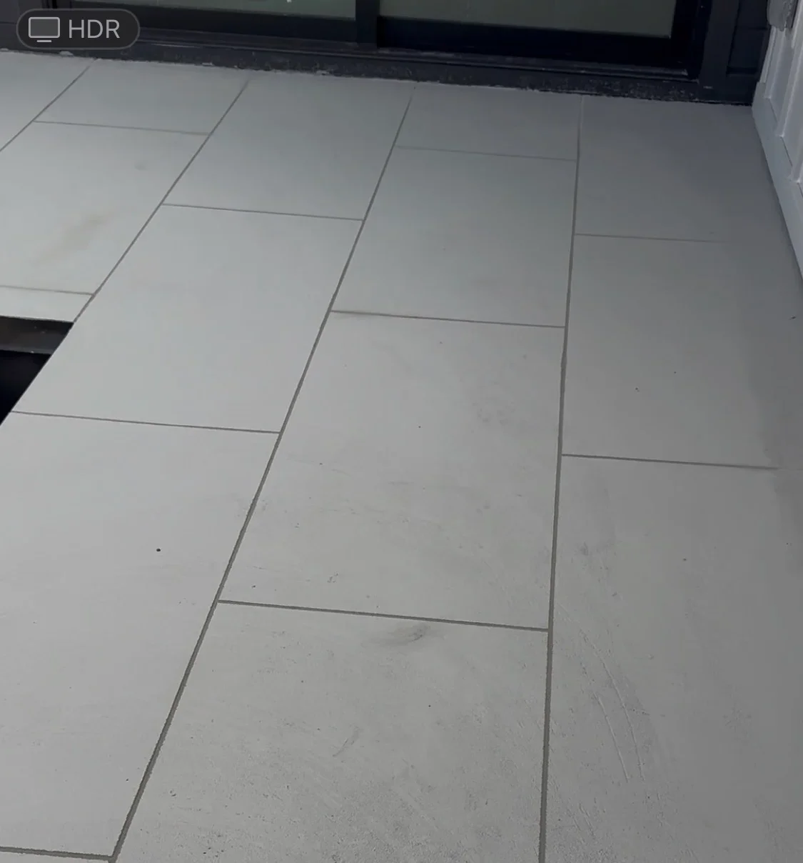 Large format gray porcelain tiles installed in running bond pattern with gray grout lines