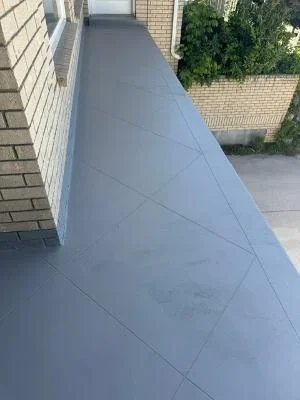 Gray deck coating with grid pattern on residential outdoor deck next to brick home