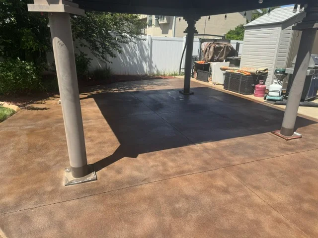 Dark deck coating applied to concrete patio with pergola and support posts