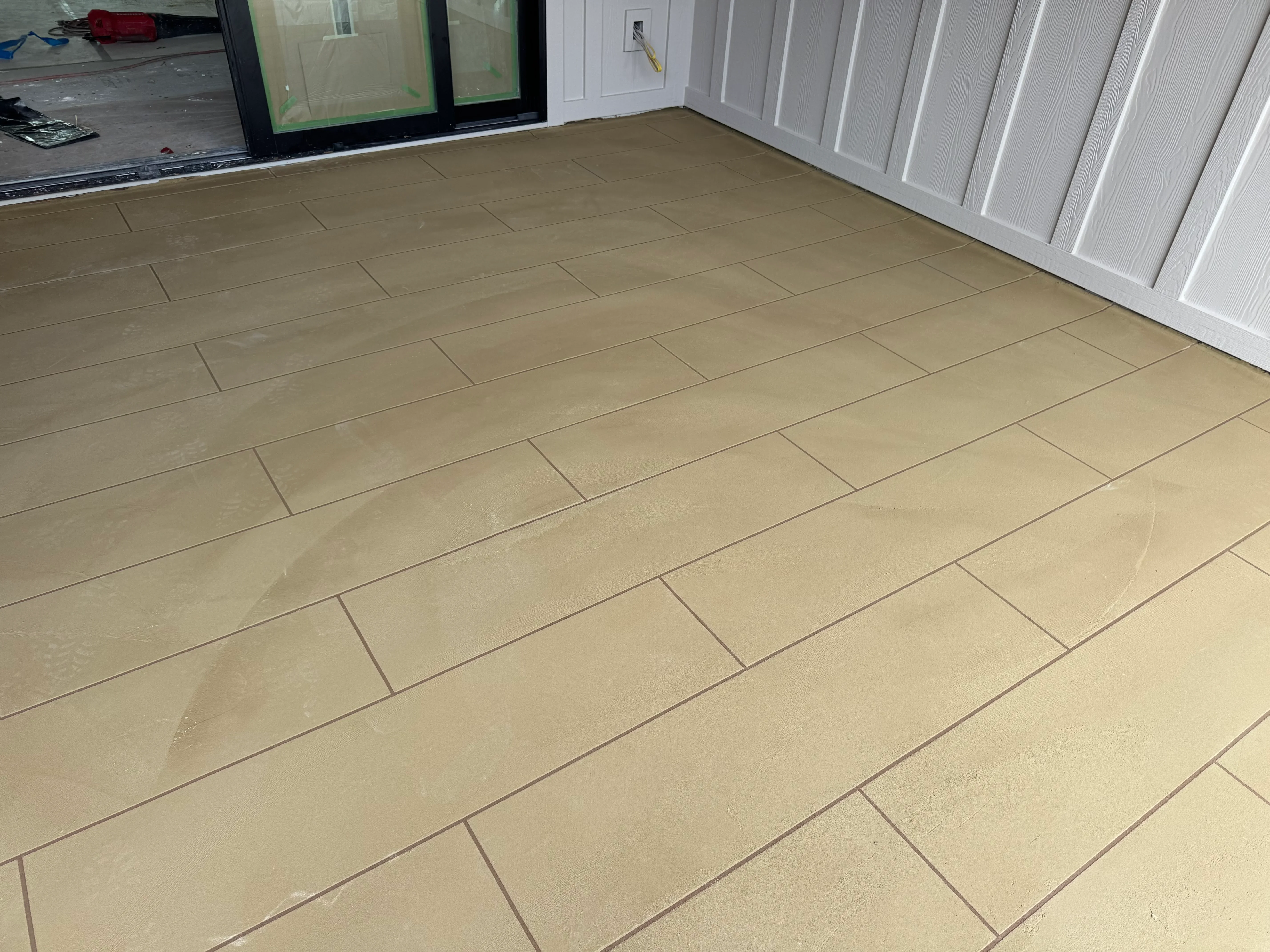 Beige ceramic tile floor with herringbone pattern and grout lines in garage space