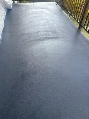 Newly coated residential deck with smooth gray protective finish and metal railing