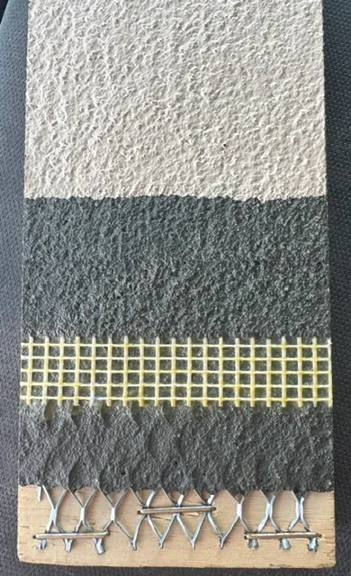 Deck coating sample showing white textured topcoat, gray base layer, mesh reinforcement, and fasteners