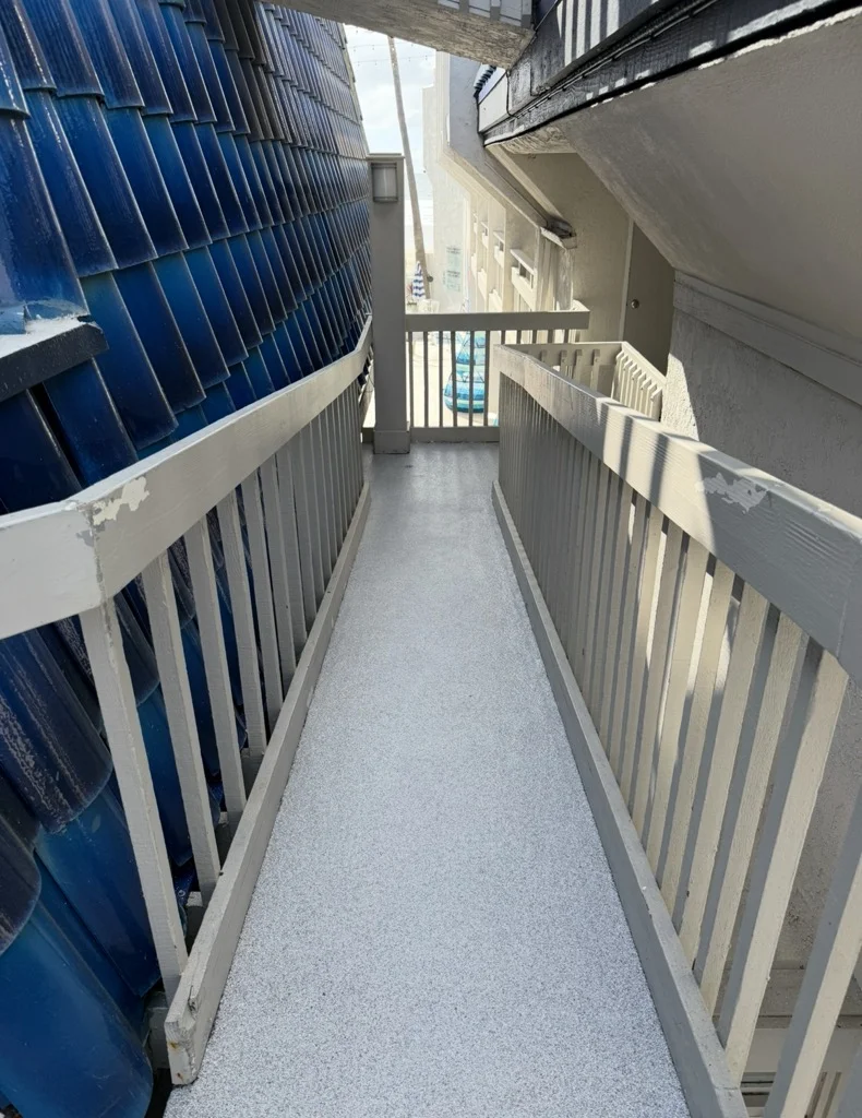 White-railed residential deck with gray protective coating and blue metal roof structure