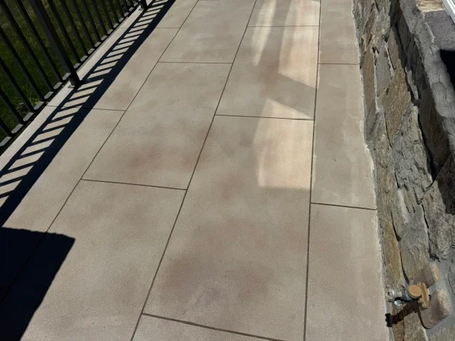 Large gray concrete pavers in running bond pattern on residential deck with metal railing