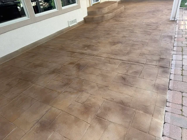 Stamped concrete patio with wood-grain texture and brown protective coating finish