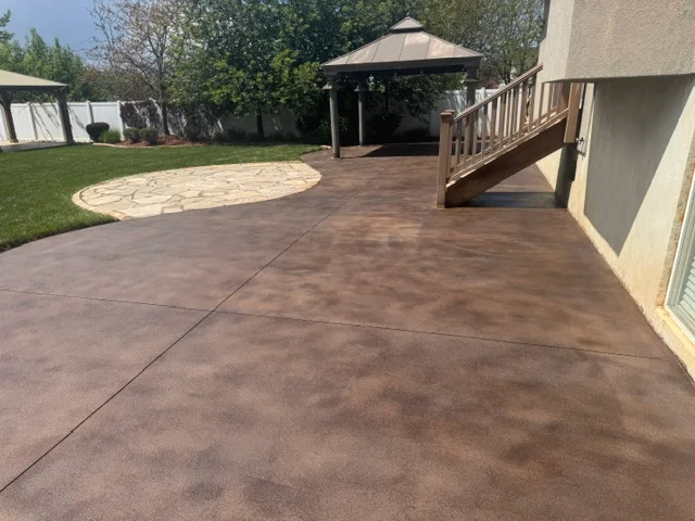 Brown stained concrete patio with circular decorative accent pattern and control joints