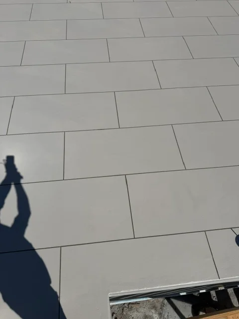 Large gray porcelain deck tiles installed in running bond pattern with uniform grout joints