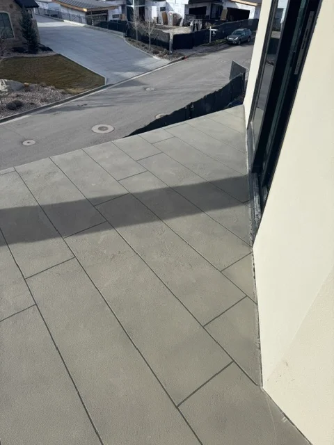 Gray deck coating on residential patio with grout lines and drainage details