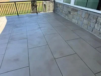 Large porcelain pavers in running bond pattern with stone wall and metal railing