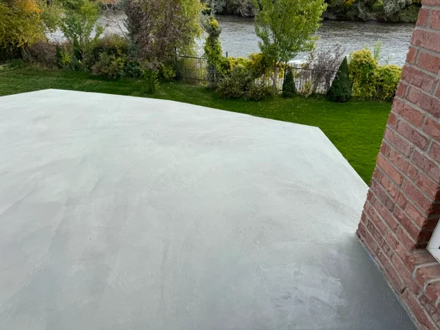 Light gray deck coating on large residential deck next to brick home with water view