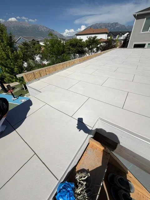 Light gray coated rooftop deck with large format tiles and wood perimeter edge detail