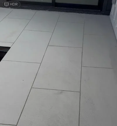 Large gray porcelain tiles in running bond pattern on exterior deck with grout lines